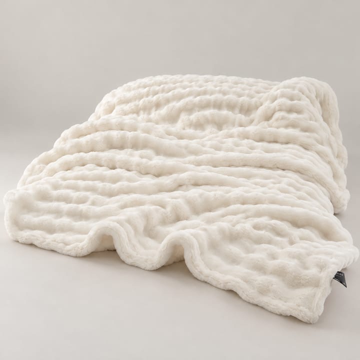 White wave stripe faux fur throw spread across a bed with a book