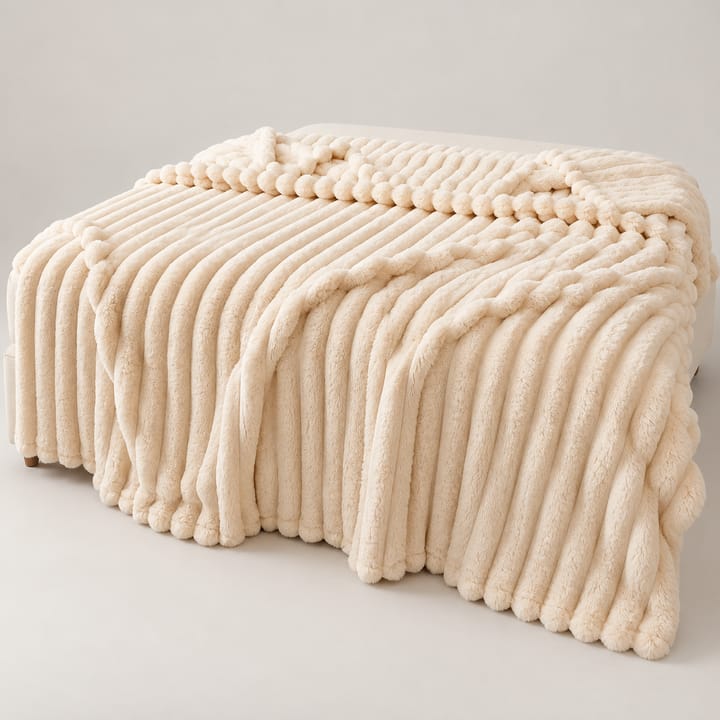 Cream ribbed faux fur throw spread across a bed with cream pillows