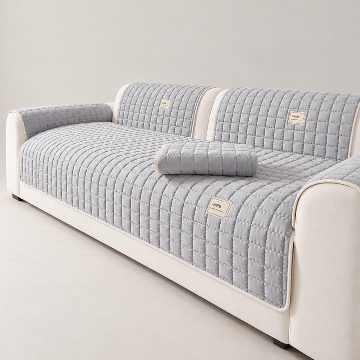 Light gray quilted couch cover on the seat of a white sofa