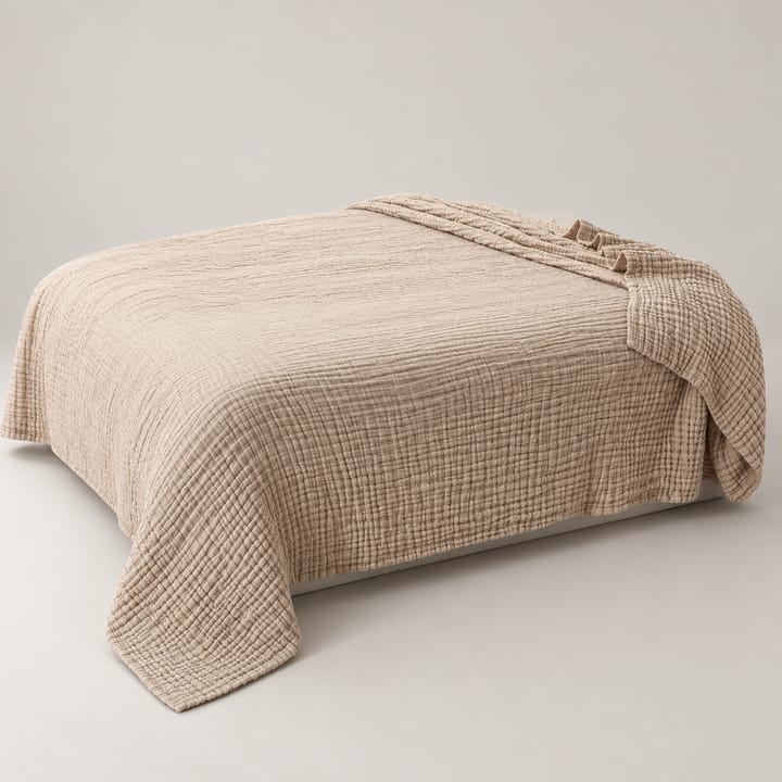 Greige crinkle gauze cotton throw spread across a bed